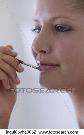 Young woman applying lipstick View Large Photo Image Stock Image - Young woman applying lipstick. Fotosearch