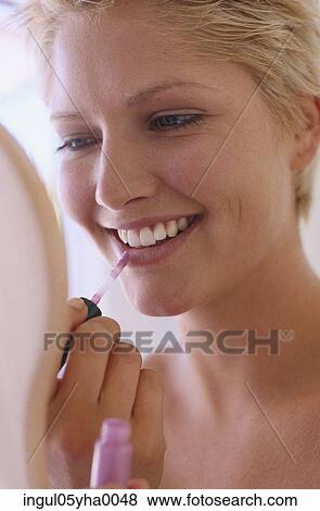 Young woman applying lipstick View Large Photo Image Stock Photo - Young woman applying lipstick. Fotosearch