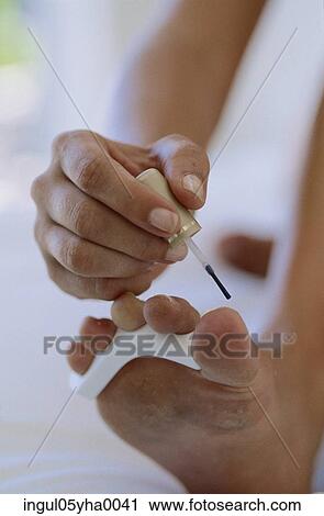 Young woman applying nail polish on her toe nails View Large Photo Image Stock Image - Young woman applying nail polish on her toe nails. Fotosearch