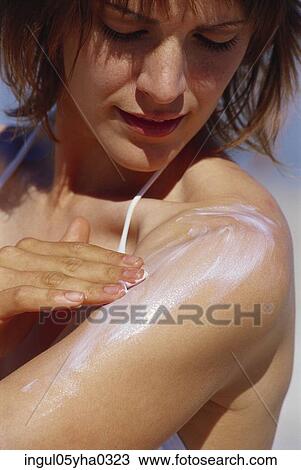 Stock Image - Young woman applying suntan lotion. Fotosearch