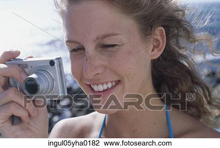 Stock Image - Young woman holding a digital camera. Fotosearch