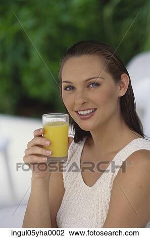 Stock Image - Young woman holding a glass of juice. Fotosearch
