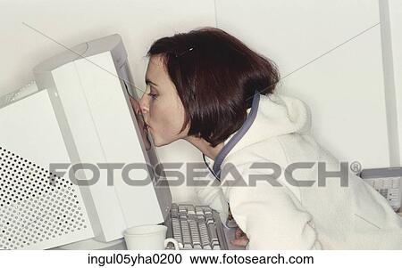 Stock Image - Young woman kissing a computer monitor. Fotosearch