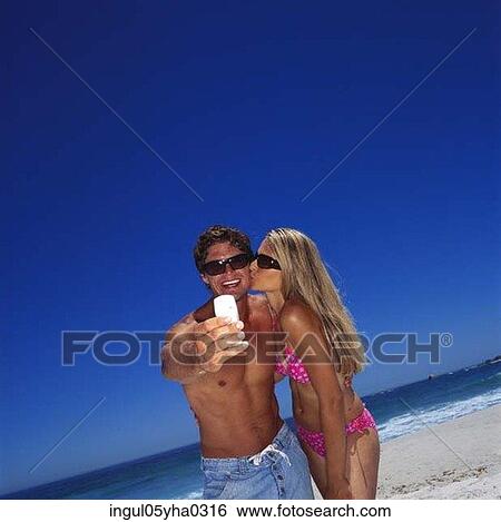 Young woman kissing a young man on the beach View Large Photo Image Stock Photograph - Young woman kissing a young man on the beach. Fotosearch