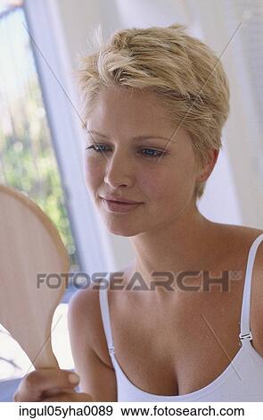 Young woman looking into a mirror View Large Photo Image Stock Photo - Young woman looking into a mirror. Fotosearch