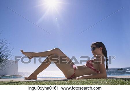 Young woman lying down on a lawn View Large Photo Image Stock Image - Young woman lying down on a lawn. Fotosearch