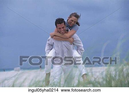 Young woman riding piggyback on a young man View Large Photo Image Picture - Young woman riding piggyback on a young man. Fotosearch