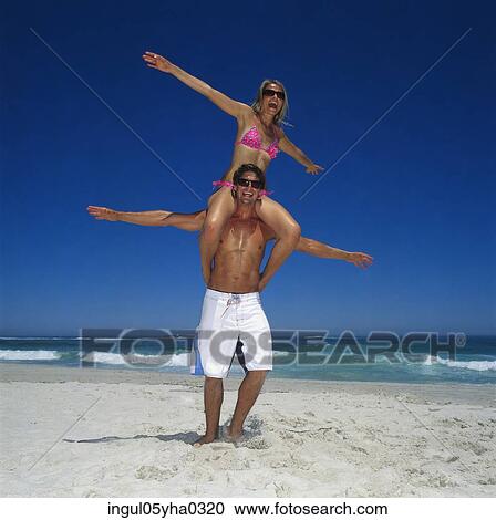 Stock Image - Young woman sitting on a young man's shoulders. Fotosearch