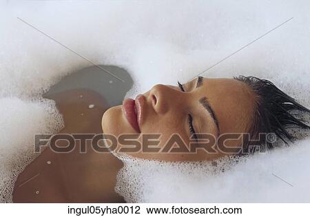 Stock Image - Young woman taking a bubble bath. Fotosearch