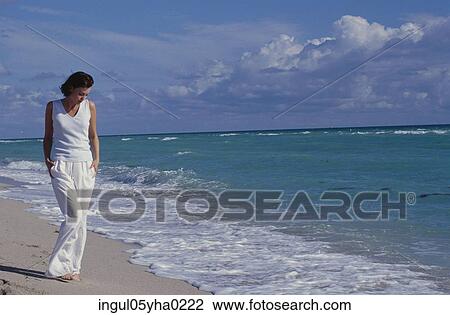 Stock Image - Young woman walking on the beach. Fotosearch