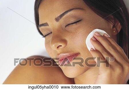Young woman wiping her face with a cotton wool pad View Large Photo Image Stock Image - Young woman wiping her face with a cotton wool pad. Fotosearch