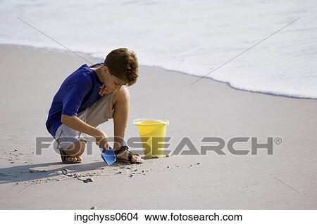 people, water, playing, beach, shorts, boy, shovel View Large Photo Image Picture - people, water, playing, beach, shorts, boy, shovel. Fotosearch