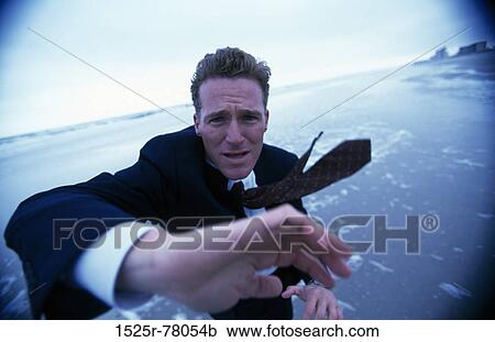 Stock Image - Businessman standing on the beach. Fotosearch