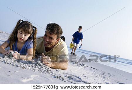 Father with his daughter making a sand castle on the beach View Large Photo Image Stock Image - Father with his daughter making a sand castle on the beach. Fotosearch