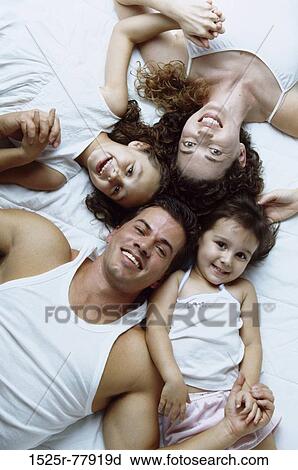 High angle view of parents lying on a bed with their children View Large Photo Image Stock Image - High angle view of parents lying on a bed with their children. Fotosearch