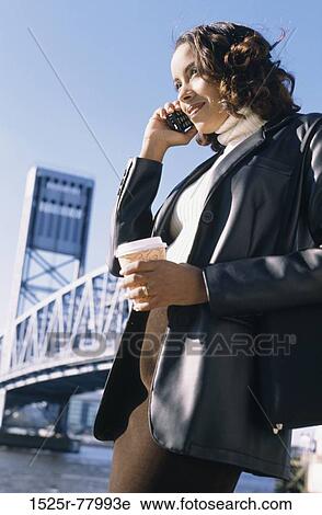 Low angle view of a young woman talking on a mobile phone View Large Photo Image Stock Image - Low angle view of a young woman talking on a mobile phone. Fotosearch
