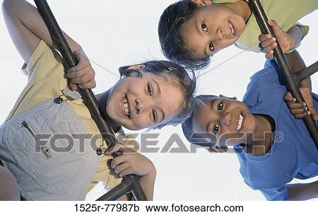 Low angle view of two boys and a girl on a jungle gym View Large Photo Image Stock Image - Low angle view of two boys and a girl on a jungle gym. Fotosearch