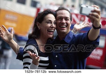 Mid adult couple taking a photograph of themselves View Large Photo Image Stock Image - Mid adult couple taking a photograph of themselves. Fotosearch