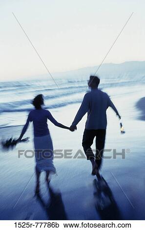 Rear view of a mid adult couple walking on the beach View Large Photo Image Stock Image - Rear view of a mid adult couple walking on the beach. Fotosearch