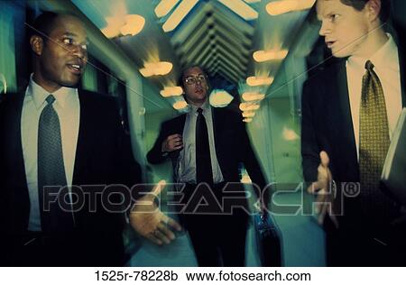 Three businessmen walking in a corridor View Large Photo Image Stock Image - Three businessmen walking in a corridor. Fotosearch