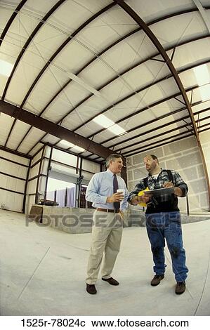 Stock Image - Two mature men standing in a warehouse. Fotosearch