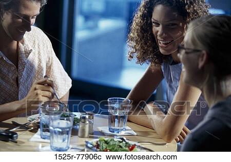 Two young women and a young man sitting in a restaurant View Large Photo Image Stock Image - Two young women and a young man sitting in a restaurant. Fotosearch