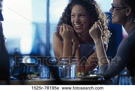Two young women and a young man talking in a restaurant View Large Photo Image Stock Image - Two young women and a young man talking in a restaurant. Fotosearch
