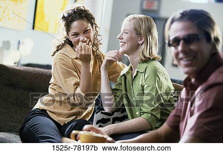 Two young women and young man sitting in a restaurant View Large Photo Image Stock Image - Two young women and young man sitting in a restaurant. Fotosearch