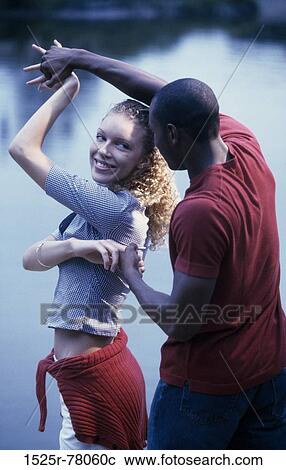 Stock Image - Young couple dancing by a lake. Fotosearch