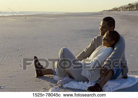 Young couple sitting together on the beach View Large Photo Image Stock Image - Young couple sitting together on the beach. Fotosearch