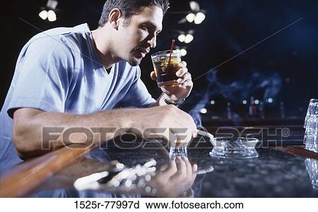 Young man smoking a cigarette and drinking alcohol View Large Photo Image Stock Image - Young man smoking a cigarette and drinking alcohol. Fotosearch