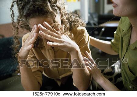 Stock Image - Young woman consoling another. Fotosearch