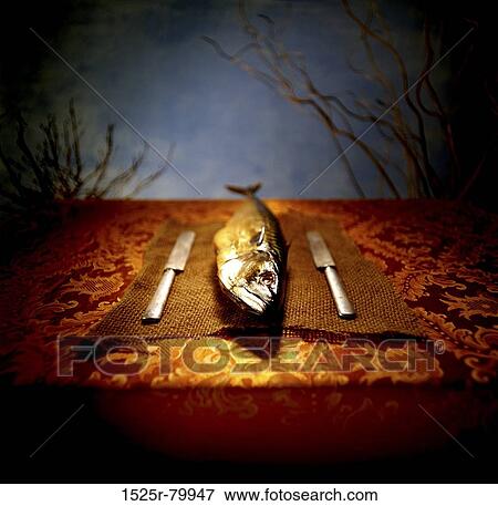 Stock Photo - Close-up of a fish with two knives on a mat. Fotosearch