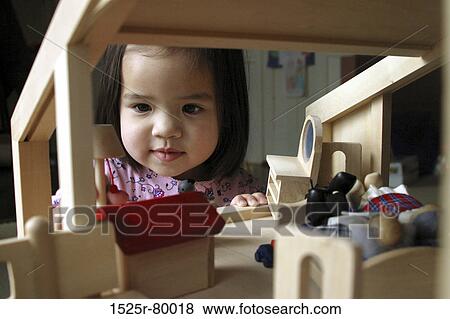 Close-up of a girl playing with a dollhouse View Large Photo Image Stock Photo - Close-up of a girl playing with a dollhouse. Fotosearch
