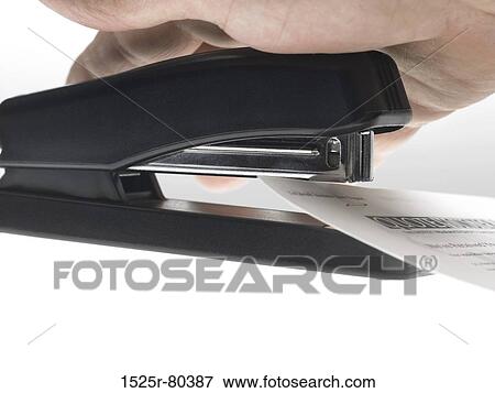 Stock Photo - Close-up of a person's hand stapling a paper. Fotosearch