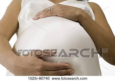 Close-up of a pregnant woman touching her abdomen View Large Photo Image Stock Image - Close-up of a pregnant woman touching her abdomen. Fotosearch