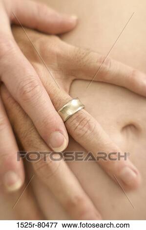 Close-up of a woman? ÇÖs hand holding a man? ÇÖs hand on her abdomen View Large Photo Image Stock Photo - Close-up of a woman? ÇÖs hand holding a man? ÇÖs hand on her abdomen. Fotosearch