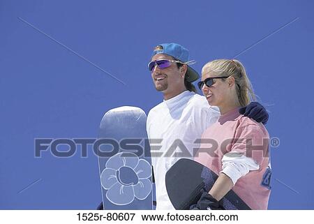 Stock Photo - Close-up of a young couple holding snowboards. Fotosearch