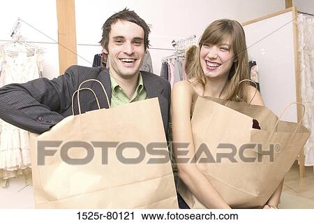 Close-up of a young couple standing in a clothing store and carrying shopping bags View Large Photo Image Stock Image - Close-up of a young couple standing in a clothing store and carrying shopping bags. Fotosearch