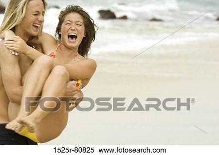 Close-up of a young man carrying a young woman on the beach View Large Photo Image Stock Photography - Close-up of a young man carrying a young woman on the beach. Fotosearch