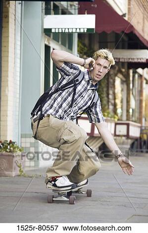 Close-up of a young man on a skateboard and using a mobile phone View Large Photo Image Stock Photo - Close-up of a young man on a skateboard and using a mobile phone. Fotosearch
