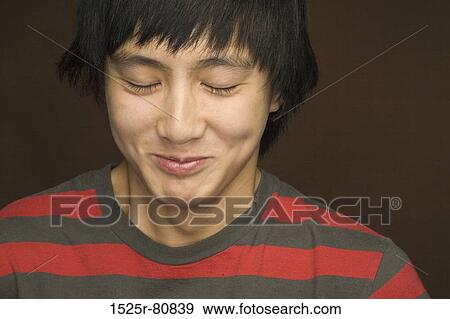 Close-up of a young man smirking View Large Photo Image Stock Photo - Close-up of a young man smirking. Fotosearch