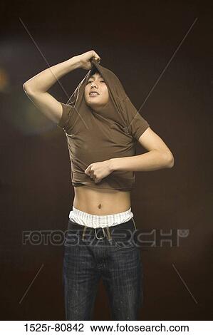 Stock Image - Close-up of a young man taking off his t-shirt. Fotosearch
