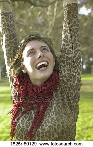 Close-up of a young woman laughing with her arms raised View Large Photo Image Stock Photo - Close-up of a young woman laughing with her arms raised. Fotosearch