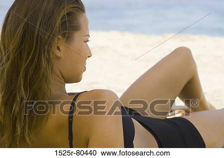 Close-up of a young woman reclining on the beach View Large Photo Image Stock Image - Close-up of a young woman reclining on the beach. Fotosearch