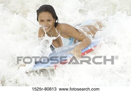 Stock Image - Close-up of a young woman surfing with a surfboard. Fotosearch