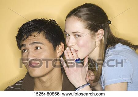 Close-up of a young woman whispering into a young man's ear View Large Photo Image Stock Photograph - Close-up of a young woman whispering into a young man's ear. Fotosearch