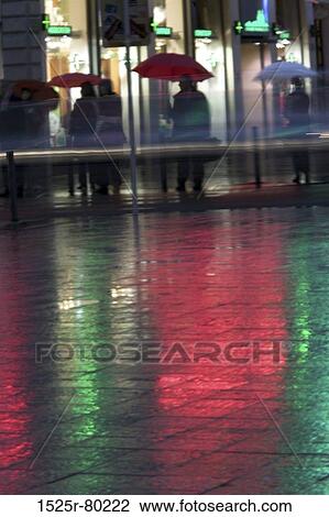 Stock Image - Group of people standing with umbrellas in the rain. Fotosearch