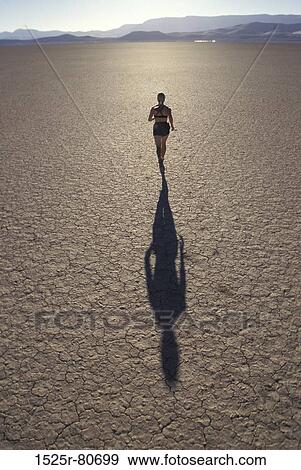 Stock Photo - High angle view of a young woman jogging on a landscape. Fotosearch