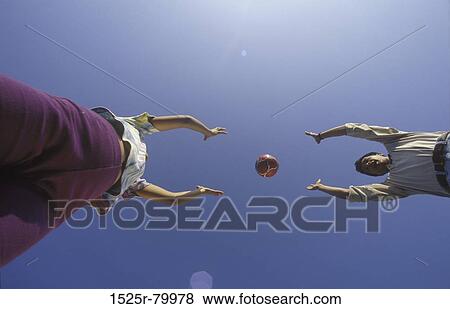 Low angle view of a young couple playing with a ball View Large Photo Image Stock Photo - Low angle view of a young couple playing with a ball. Fotosearch